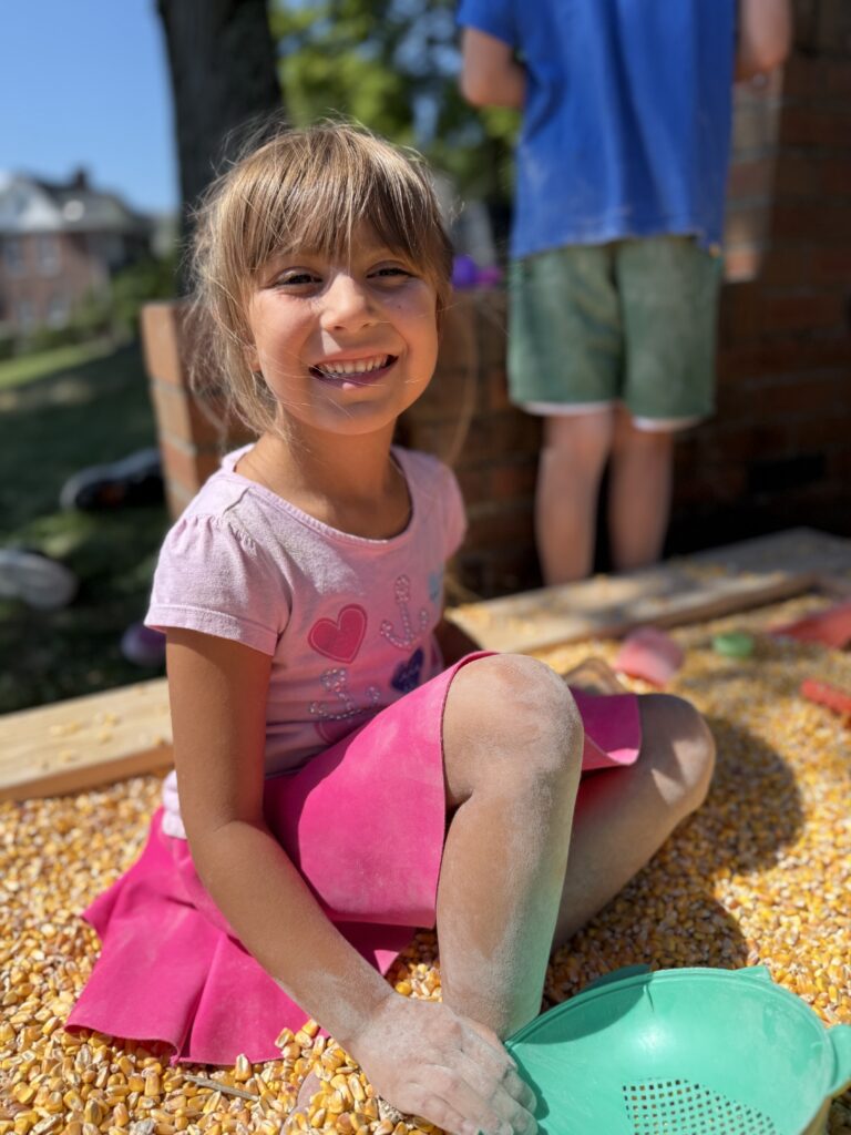 Child playing in the corn pit at Camp Fun Club
